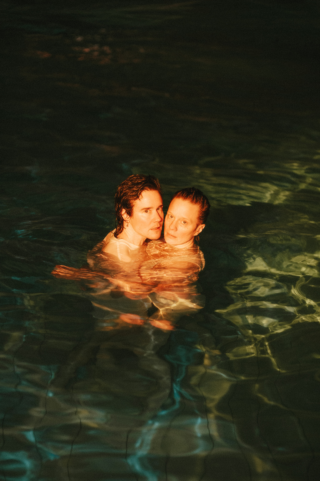 Two people in a swimming pool at night